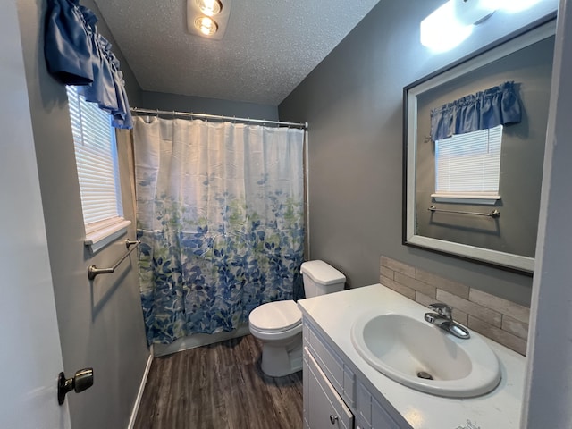 4507 54th St, Lubbock, TX 79414 - bathroom featuring wood finished floors, vanity, a textured ceiling, decorative backsplash, and shower / bath combo with shower curtain