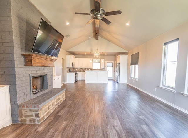 unfurnished living room featuring lofted ceiling with beams, ceiling fan, a brick fireplace, and dark hardwood / wood-style flooring