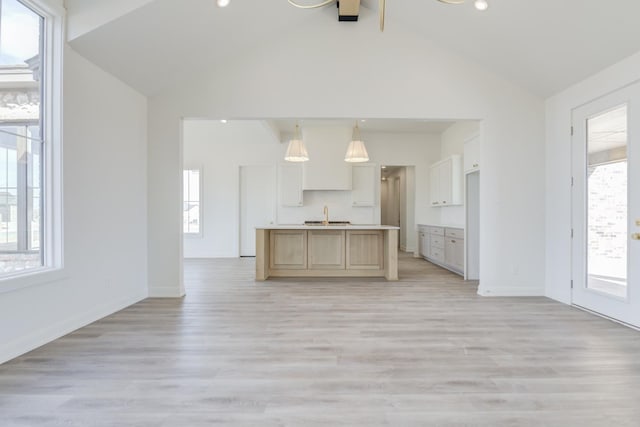 kitchen with sink, decorative light fixtures, light hardwood / wood-style floors, and a center island with sink