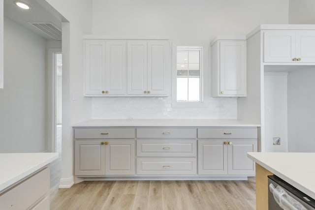 kitchen with dishwasher, backsplash, white cabinets, and light wood-type flooring