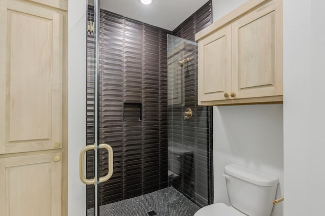 bathroom featuring a shower with shower door and toilet