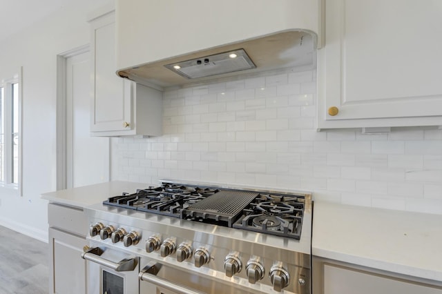 kitchen featuring backsplash, custom range hood, light hardwood / wood-style floors, high end stove, and white cabinets