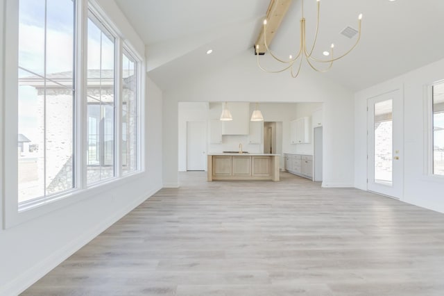 unfurnished living room with sink, a chandelier, light wood-type flooring, and vaulted ceiling with beams