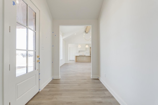 corridor with vaulted ceiling with beams, plenty of natural light, and light wood-type flooring