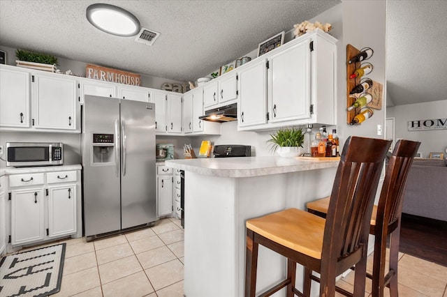 kitchen featuring a kitchen bar, a textured ceiling, appliances with stainless steel finishes, kitchen peninsula, and white cabinets