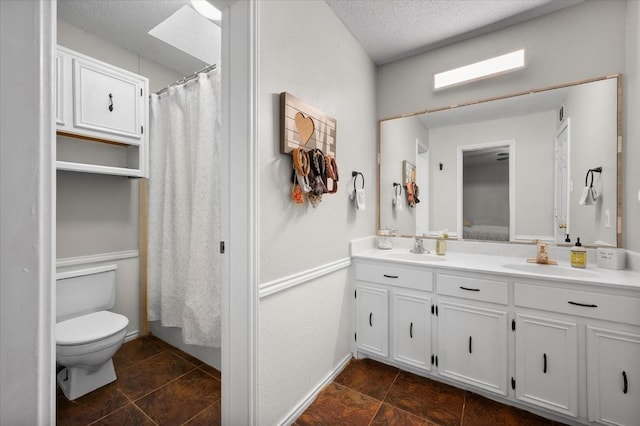 bathroom with walk in shower, toilet, a skylight, a textured ceiling, and vanity