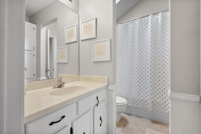 bathroom featuring vanity, toilet, tile patterned flooring, and a textured ceiling