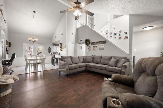 living room featuring hardwood / wood-style flooring, ceiling fan with notable chandelier, high vaulted ceiling, and a textured ceiling