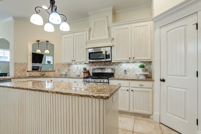 kitchen with ornamental molding, appliances with stainless steel finishes, and pendant lighting