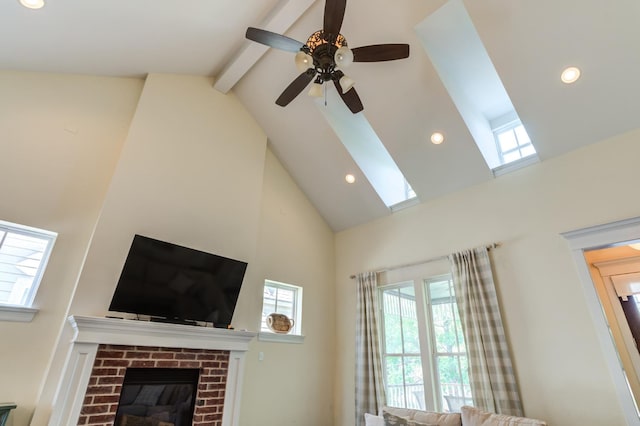 living room featuring ceiling fan, a brick fireplace, high vaulted ceiling, and beam ceiling