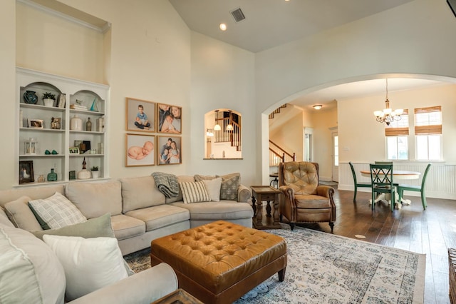 living room with a towering ceiling, dark hardwood / wood-style floors, and a notable chandelier