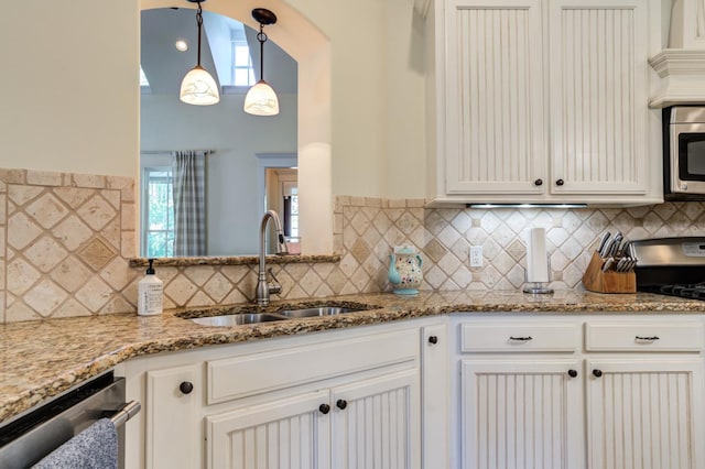 kitchen featuring sink, appliances with stainless steel finishes, white cabinetry, hanging light fixtures, and light stone countertops