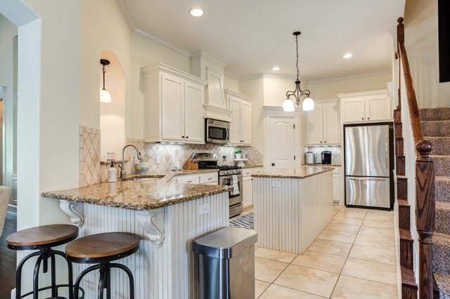 kitchen with pendant lighting, sink, kitchen peninsula, and appliances with stainless steel finishes