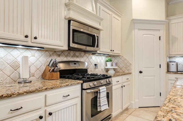 kitchen with backsplash, appliances with stainless steel finishes, light stone countertops, and light tile patterned floors