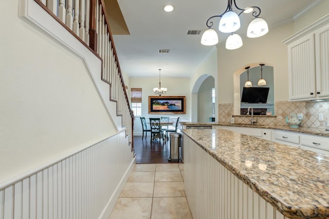 kitchen with pendant lighting, a notable chandelier, light tile patterned floors, and light stone countertops