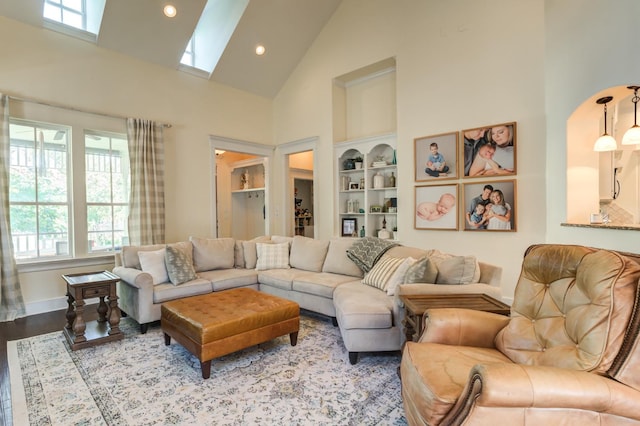 living room featuring high vaulted ceiling, built in shelves, and light hardwood / wood-style floors