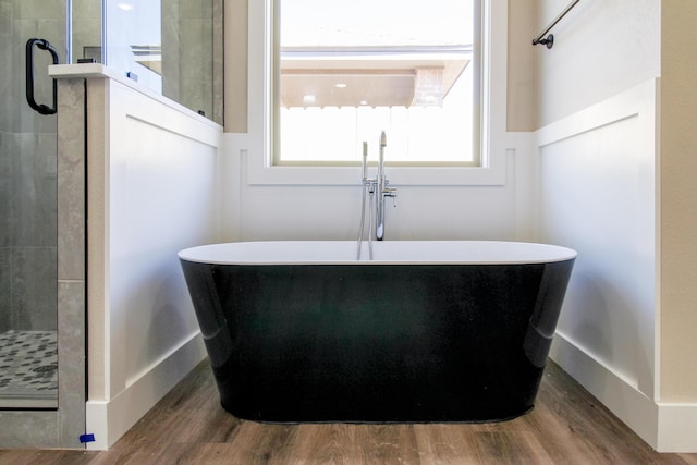 bathroom with wood finished floors, a soaking tub, a stall shower, and a sink