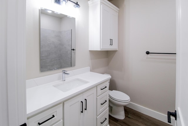bathroom with toilet, wood finished floors, vanity, and baseboards