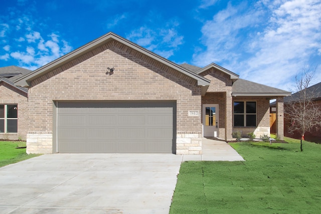 view of front of property with driveway, a front yard, an attached garage, and brick siding