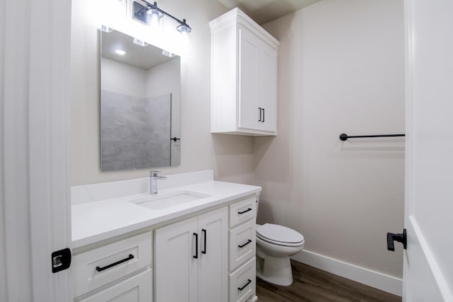 bathroom featuring baseboards, wood finished floors, toilet, and vanity
