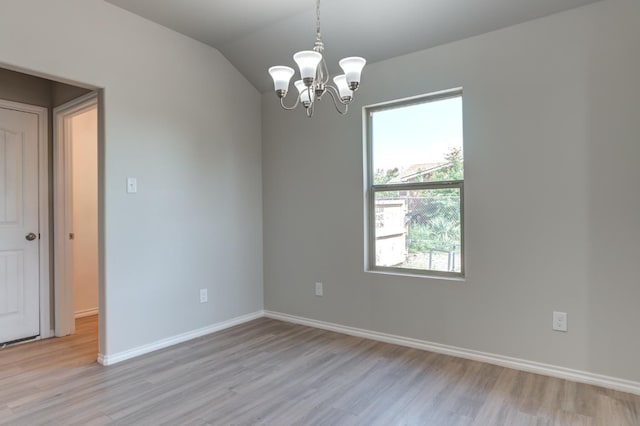 spare room with lofted ceiling, a notable chandelier, and light hardwood / wood-style flooring