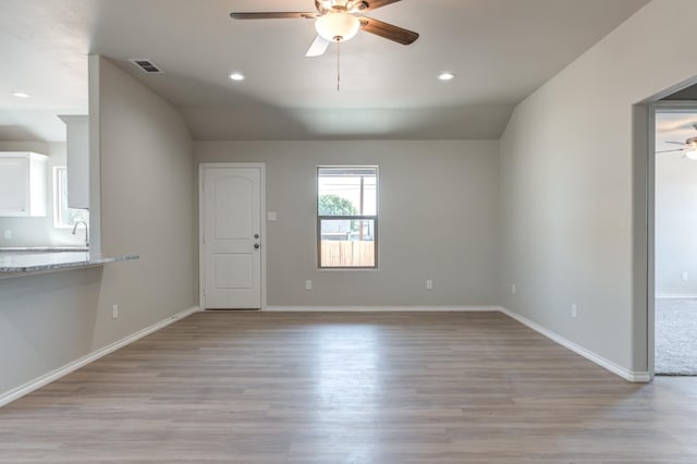 unfurnished living room with ceiling fan, vaulted ceiling, and light hardwood / wood-style flooring