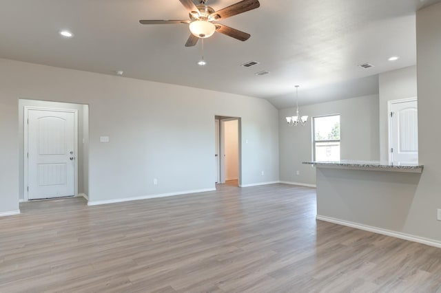 unfurnished living room with lofted ceiling, ceiling fan with notable chandelier, and light wood-type flooring