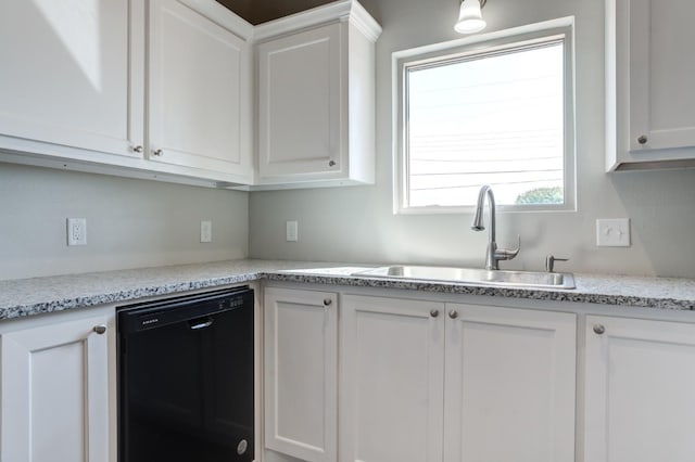 kitchen with white cabinets, light stone countertops, sink, and black dishwasher