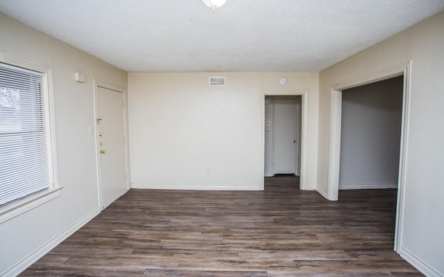 unfurnished room featuring dark wood-type flooring and a textured ceiling