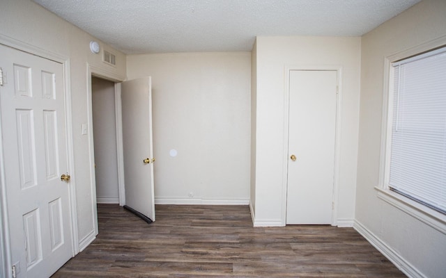 unfurnished bedroom featuring a textured ceiling and dark hardwood / wood-style flooring