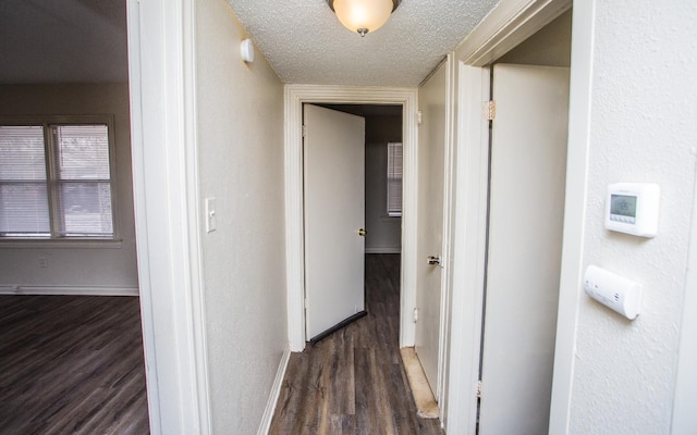 hall with dark wood-type flooring and a textured ceiling