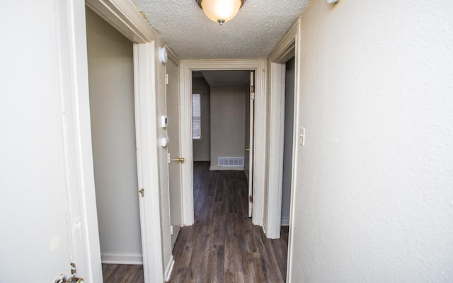 corridor with dark hardwood / wood-style flooring and a textured ceiling