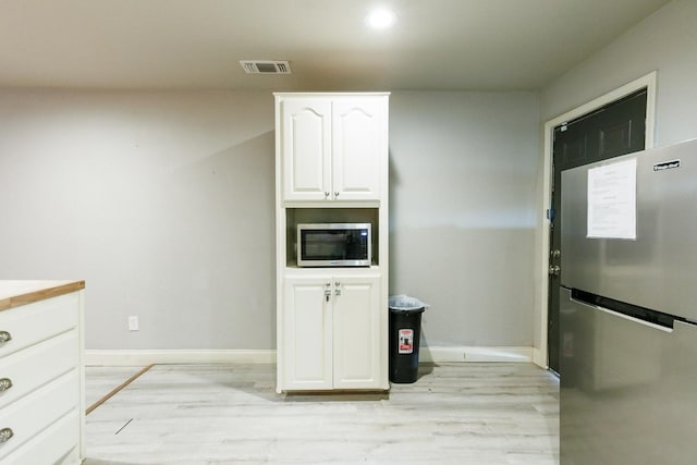 kitchen with appliances with stainless steel finishes, light hardwood / wood-style floors, and white cabinets