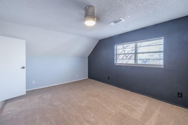 additional living space featuring lofted ceiling, carpet floors, and a textured ceiling