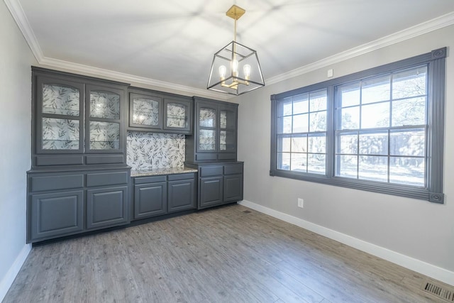 unfurnished dining area featuring a notable chandelier, crown molding, and light wood-type flooring