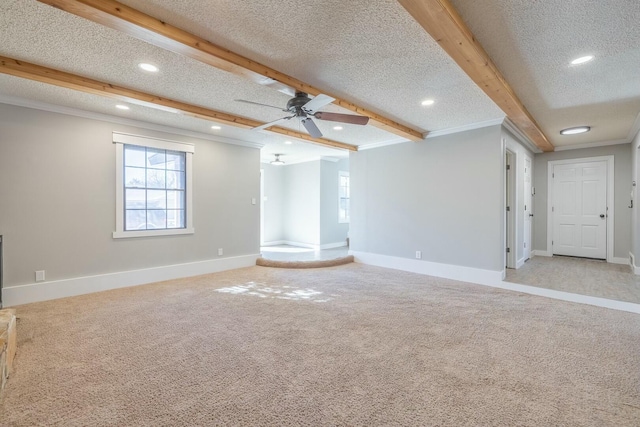 unfurnished living room featuring carpet floors, beam ceiling, ornamental molding, ceiling fan, and a textured ceiling