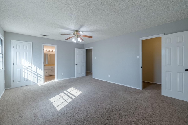 unfurnished bedroom featuring ceiling fan, carpet floors, ensuite bath, and a textured ceiling