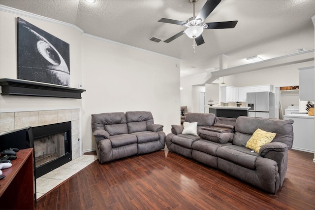 living room with a tiled fireplace, crown molding, hardwood / wood-style floors, and a textured ceiling