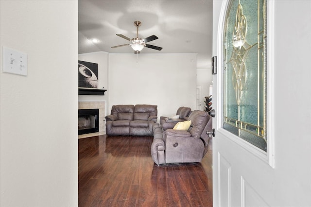 living room with a tiled fireplace, vaulted ceiling, dark hardwood / wood-style floors, and ceiling fan