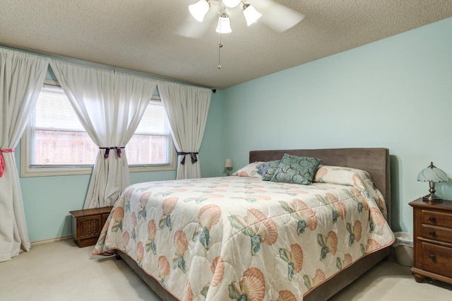 bedroom featuring light colored carpet, a textured ceiling, and ceiling fan