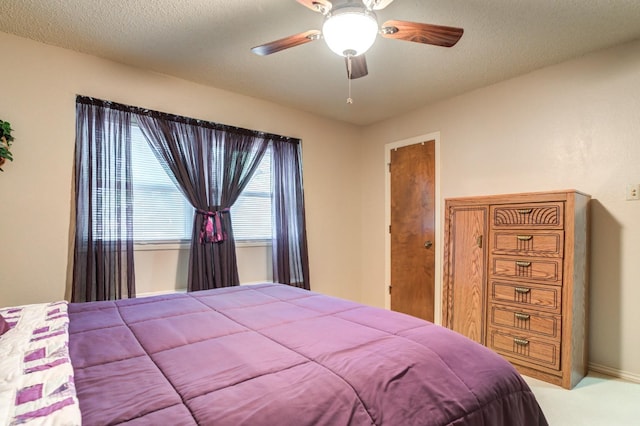 bedroom featuring light colored carpet, a textured ceiling, and ceiling fan