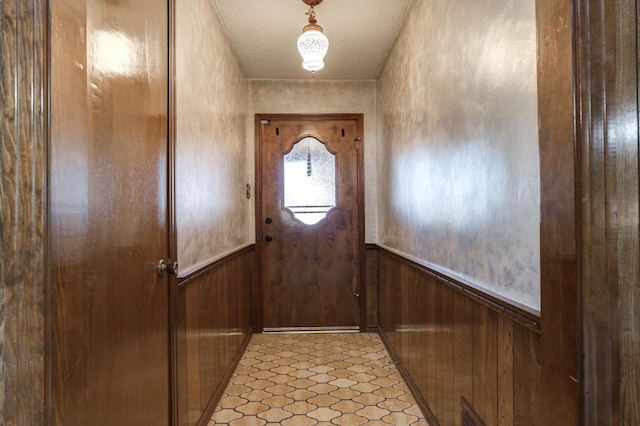 entryway with a textured ceiling and wood walls