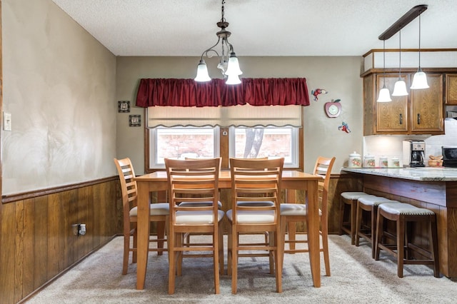 carpeted dining space featuring plenty of natural light, a chandelier, and a textured ceiling