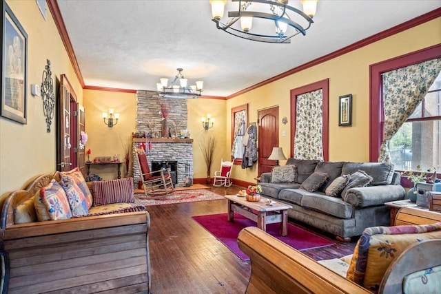 living room with ornamental molding, a fireplace, hardwood / wood-style floors, and a notable chandelier