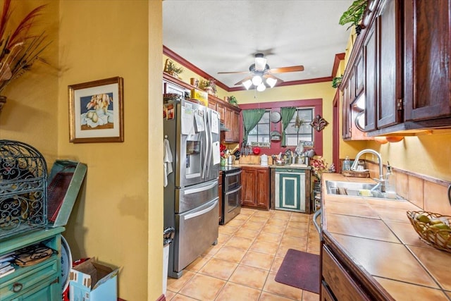 kitchen with appliances with stainless steel finishes, sink, ornamental molding, tile counters, and light tile patterned floors