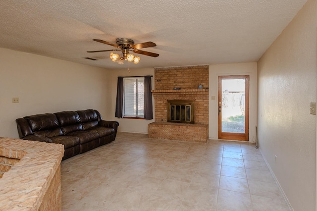 living room featuring ceiling fan, plenty of natural light, a fireplace, and a textured ceiling