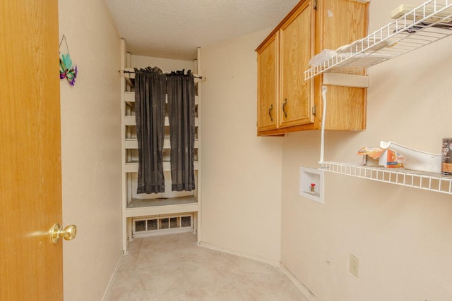 laundry room featuring washer hookup, cabinets, and a textured ceiling