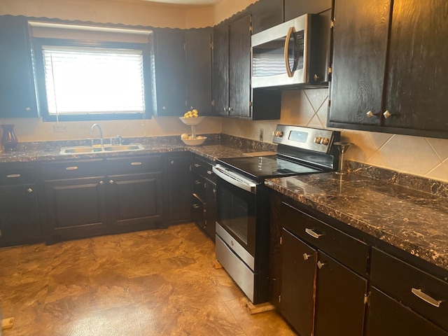 kitchen featuring sink, appliances with stainless steel finishes, dark stone countertops, dark brown cabinets, and tasteful backsplash