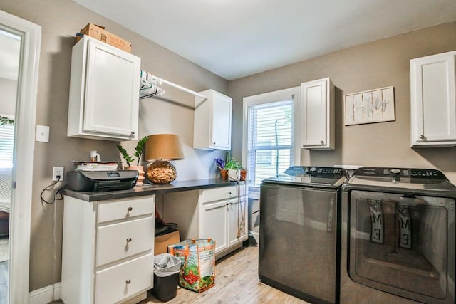 clothes washing area featuring cabinets, washing machine and clothes dryer, and light hardwood / wood-style flooring