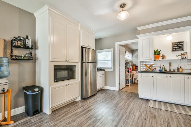 kitchen with sink, stainless steel fridge, light hardwood / wood-style floors, and white cabinets